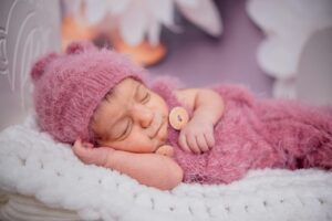 Peaceful sleeping infant in white bedding demonstrating successful sleep training results