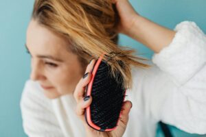 How Scalp Massage Tools Are Replacing Traditional Hair Growth Treatments Close-up of a wooden scalp massage brush being used on hair