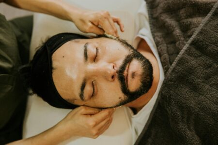 Professional spa therapist performing facial massage treatment with specialized tools