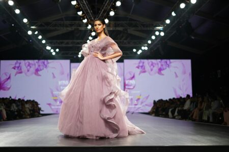 Fashion runway with dramatic lighting showcasing the evolution from traditional to digital presentations