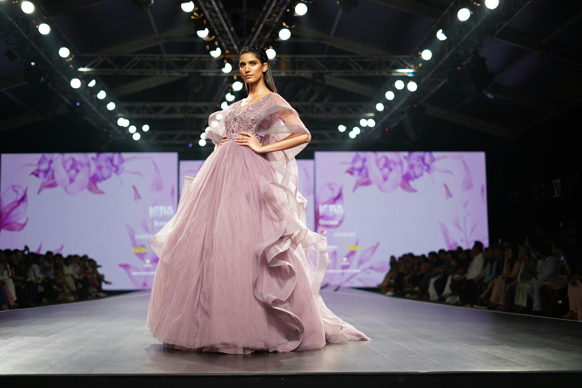 Fashion runway with dramatic lighting showcasing the evolution from traditional to digital presentations