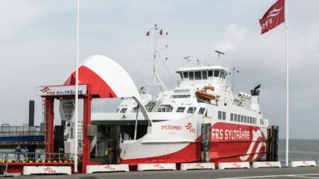 Ferry boat traveling through Copenhagen harbor with city skyline in background