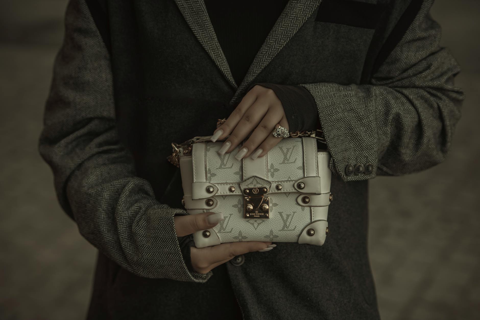 Elegant leather handbag in neutral tone positioned on marble surface with soft lighting