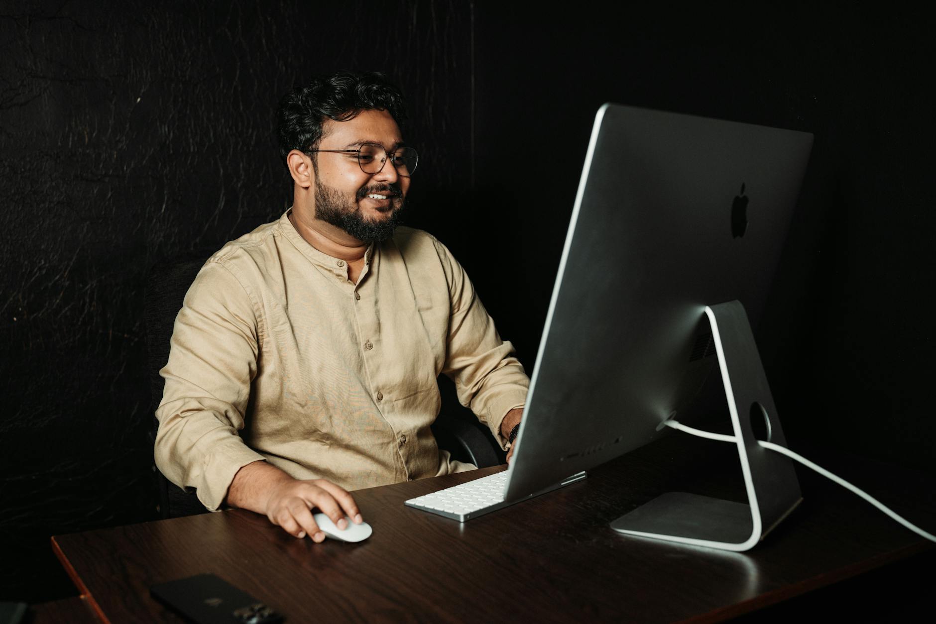 Professional office worker in business casual clothing at desk with laptop and mobile devices