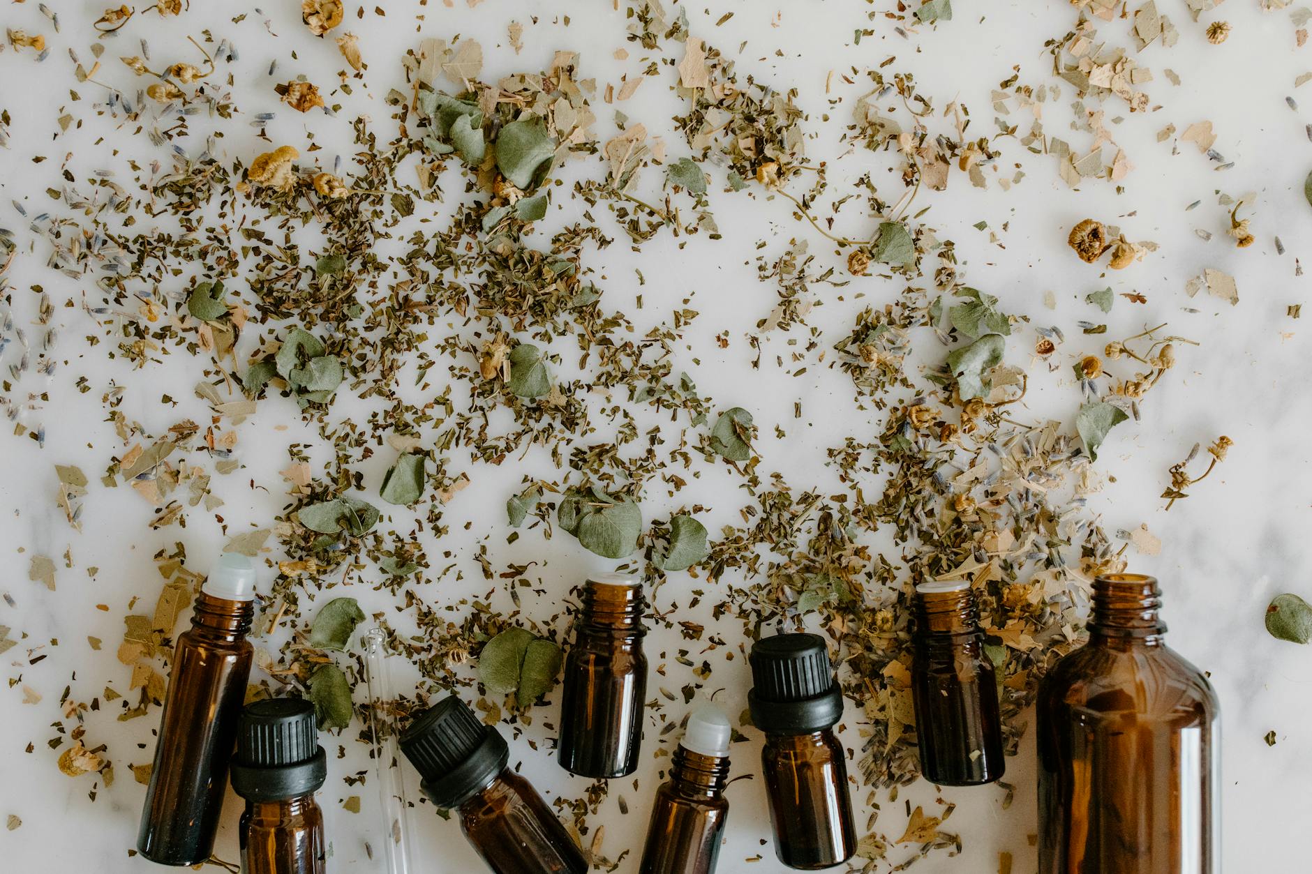 Natural herbal ingredients and oils arranged in spa setting with mortar and pestle