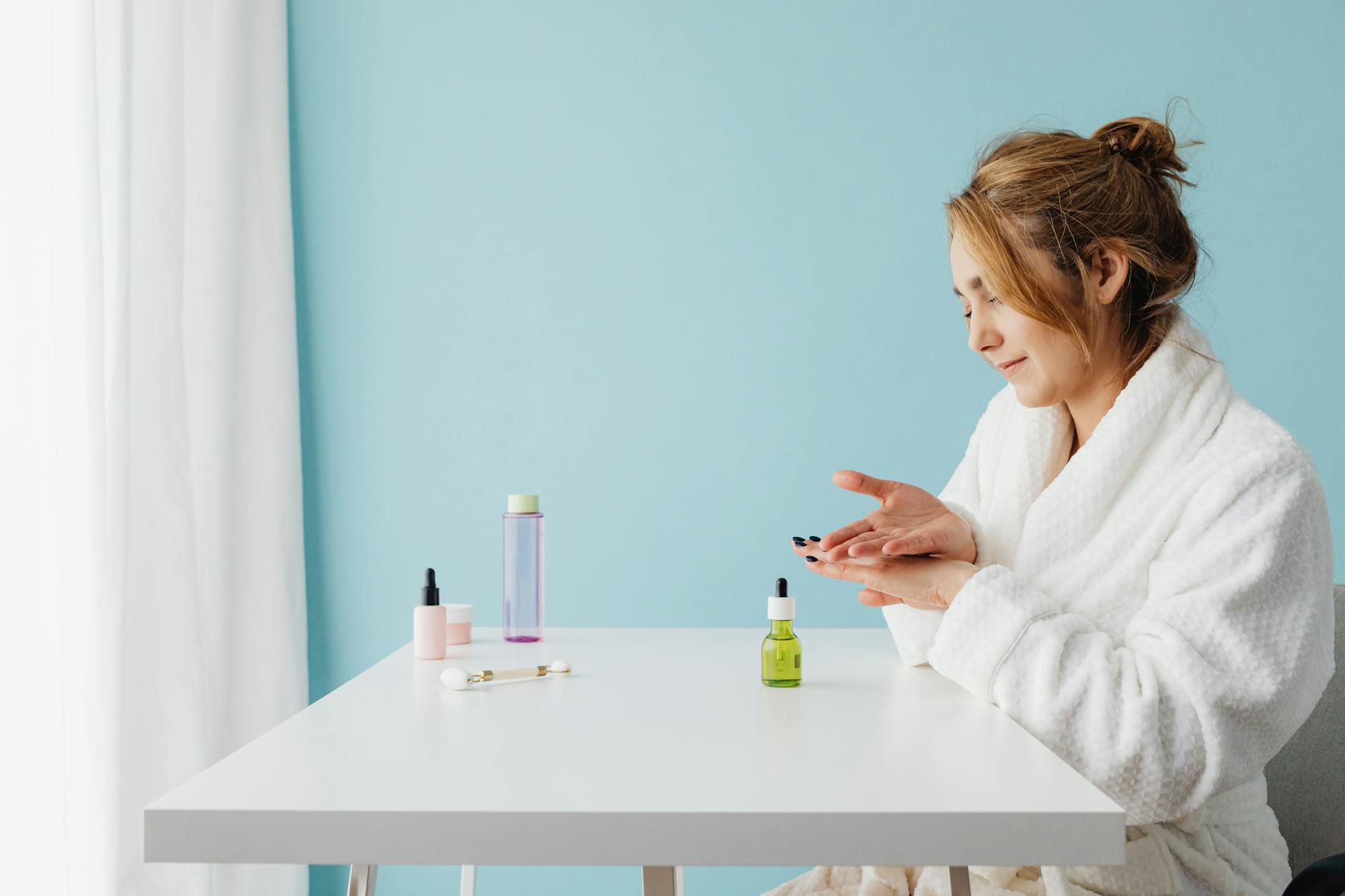 Woman applying skincare products with healthy glowing complexion