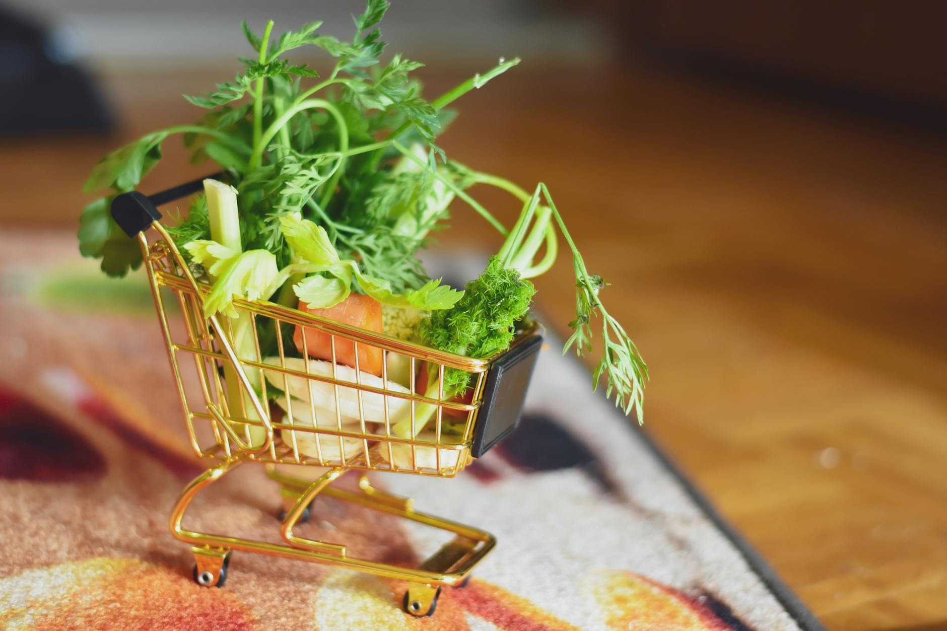 Shopping cart filled with fresh produce in grocery store setting with shoppers