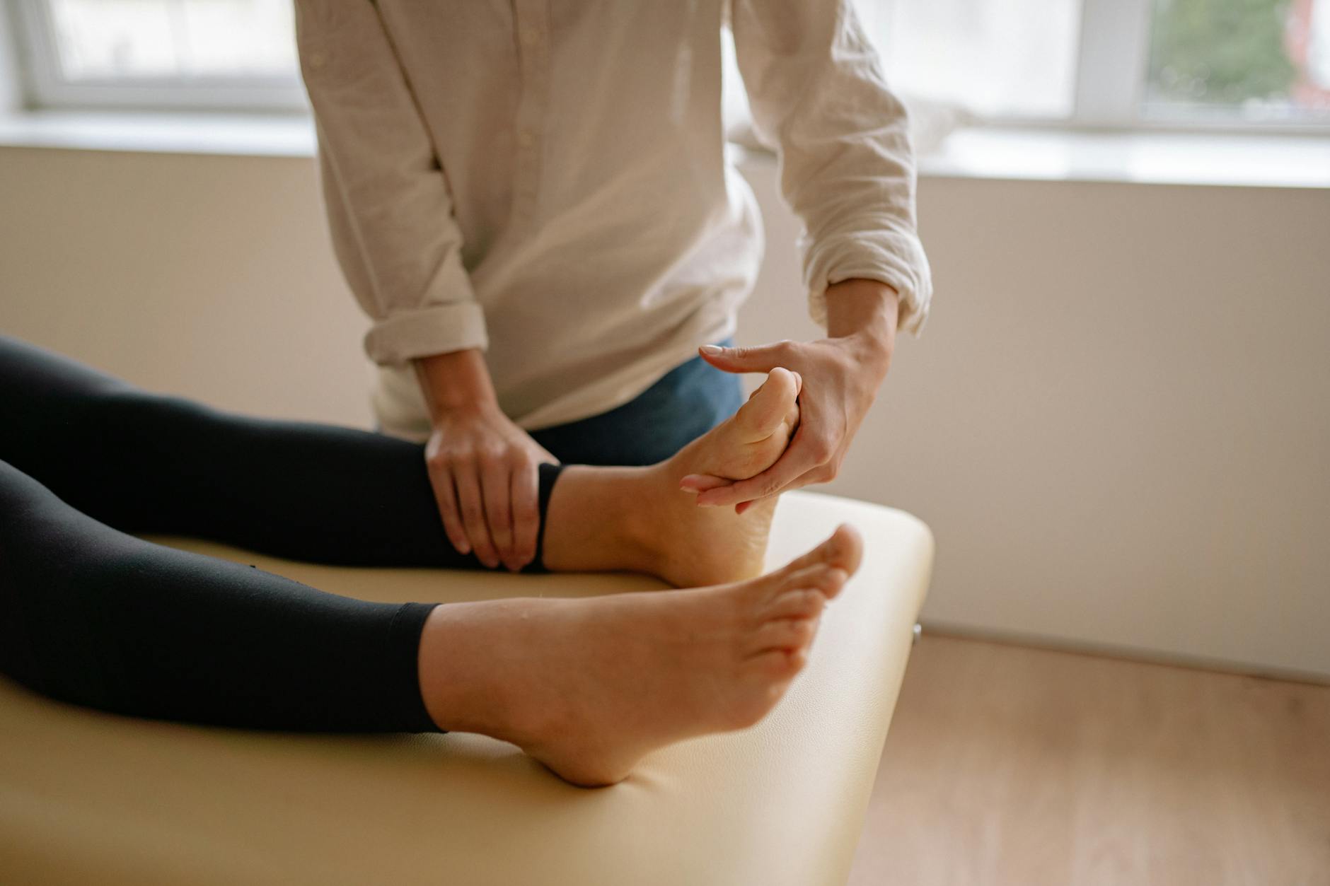 Hands applying pressure to foot pressure points during reflexology treatment session