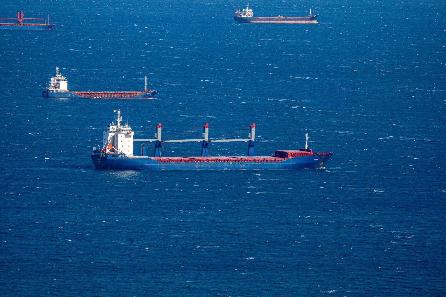 Large cargo ship navigating open ocean waters under overcast sky