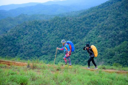 Women hiking outdoors wearing trail footwear on a forest path