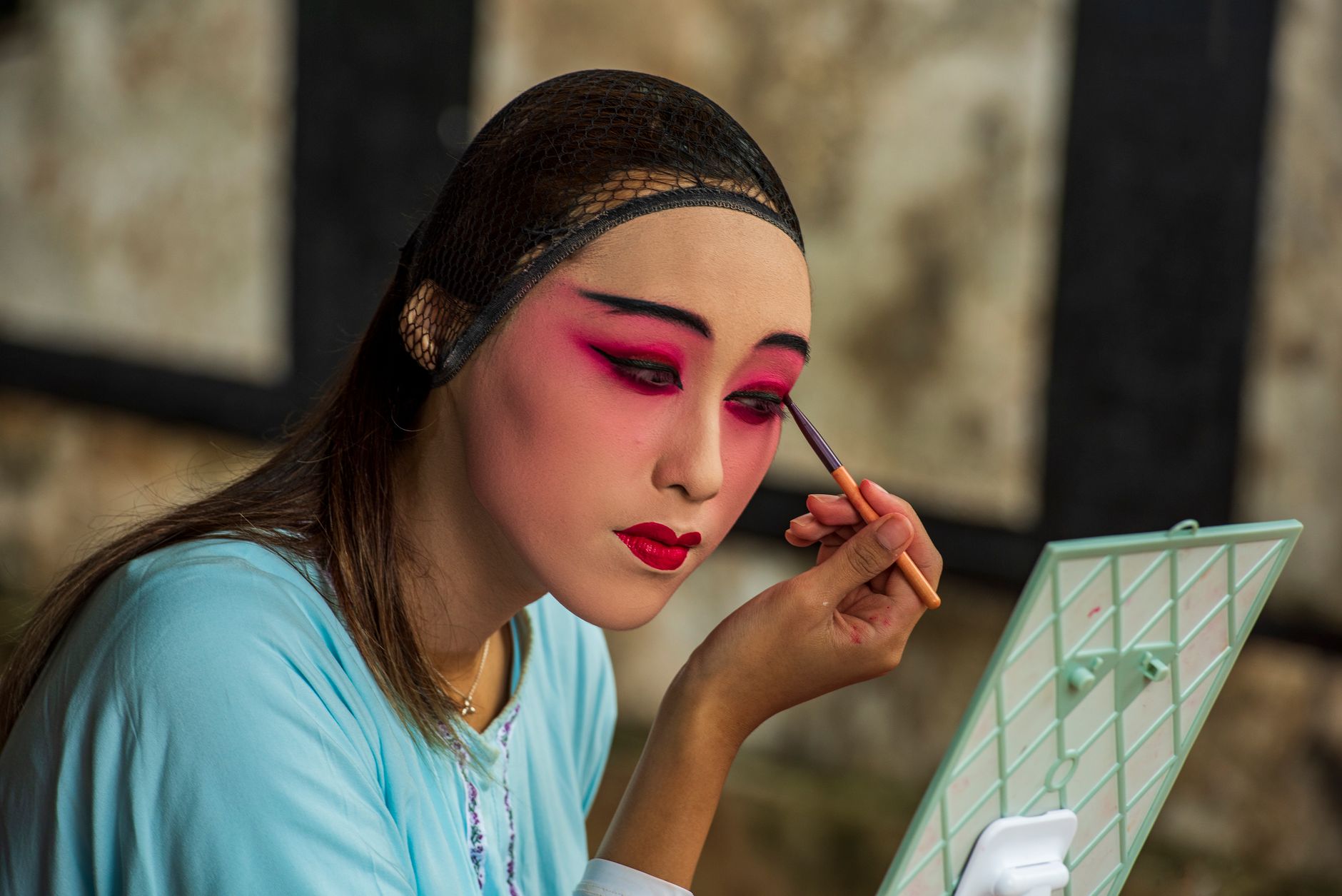 Close-up of theatrical stage makeup with bold eye and defined brows under bright light