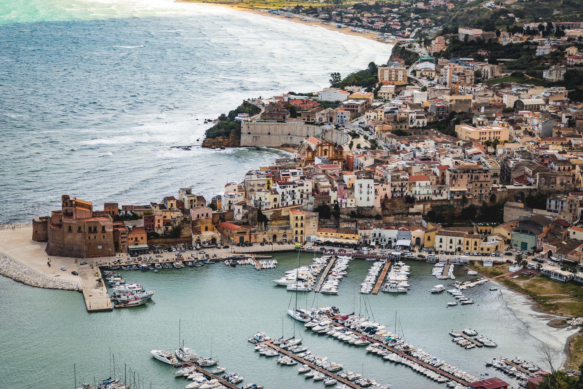 Sunlit Italian Riviera coastline with beach umbrellas and clear blue water