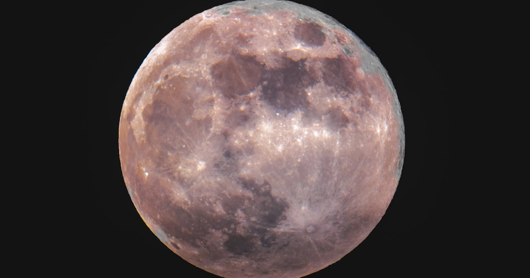 Large full moon glowing against a dark blue summer night sky