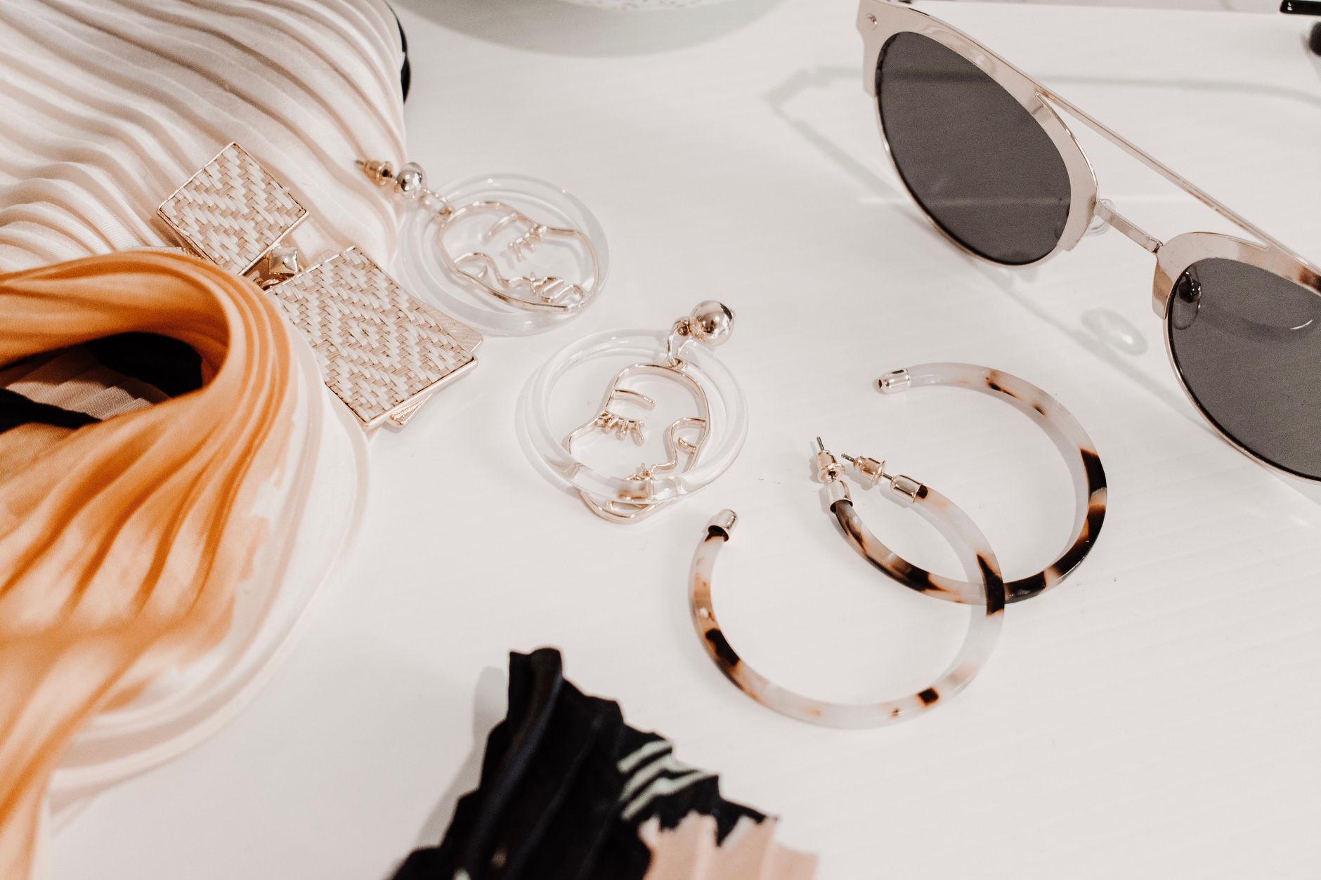 Stylish summer accessories including sunglasses and jewelry arranged on a light background
