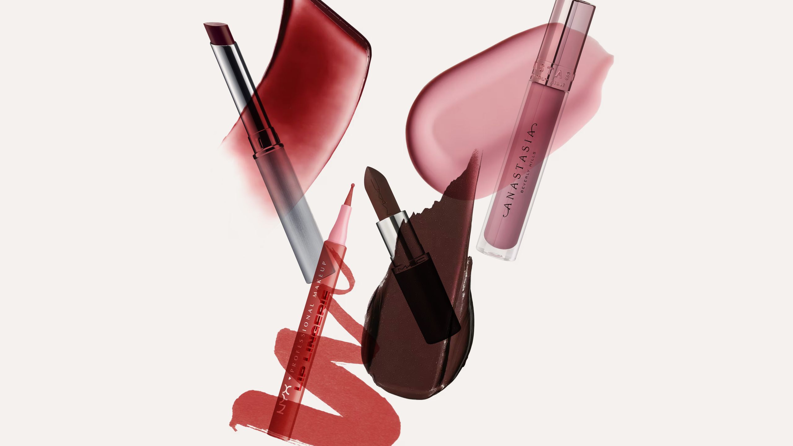 Close-up of lip gloss tubes and applicators on a pink background
