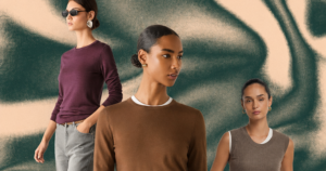 Folded luxury cashmere sweaters in neutral tones stacked on a wooden surface