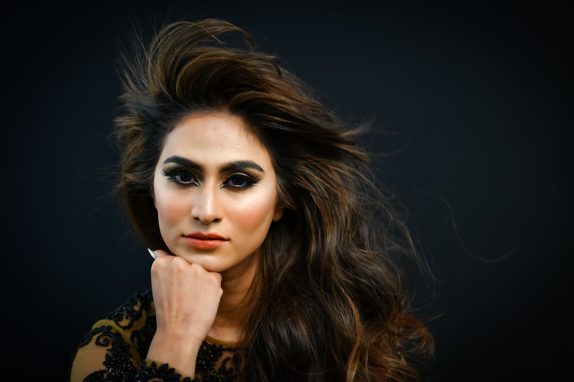 Close-up portrait of a woman with styled, colored hair under warm lighting