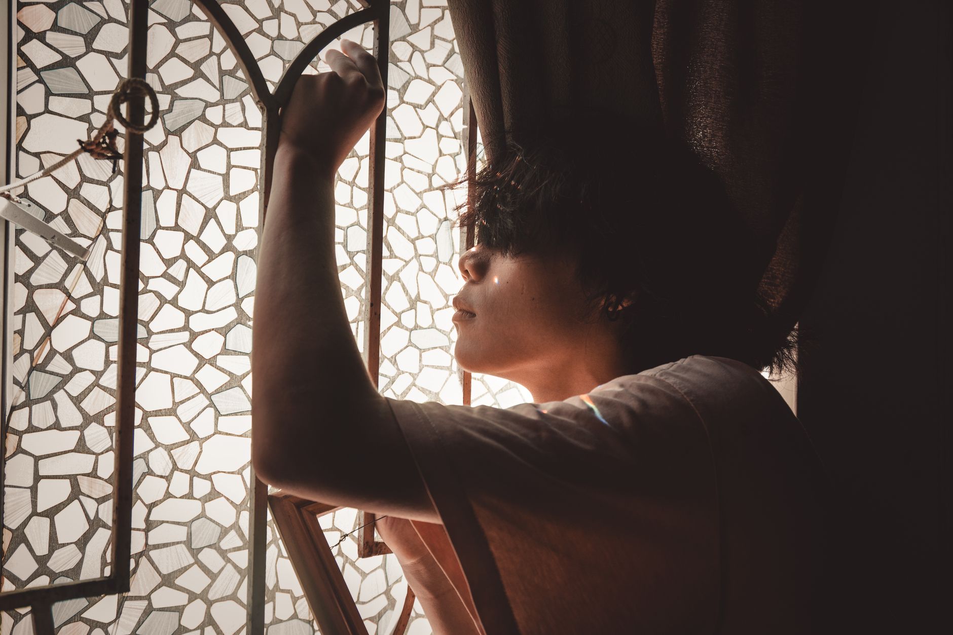 A woman sitting alone near a window, soft natural light, contemplative expression